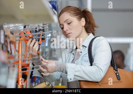 Junge Frau kauft Werkzeuge im Eisenwarenladen Stockfoto