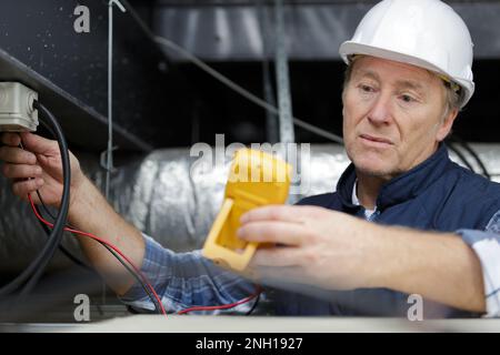 Erfahrener Elektriker mit Elektroarbeiten Stockfoto