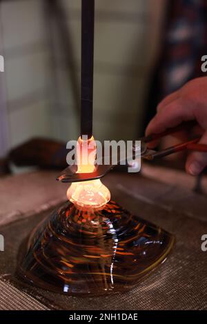 Ein Glasbläser, der ein wunderschönes Stück Glas bildet Stockfoto