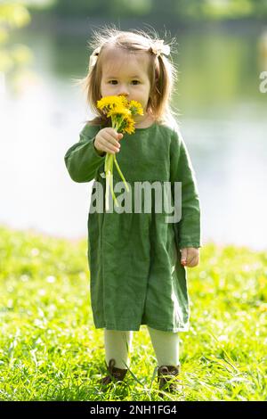 Ein kleines Mädchen mit einem Strauß Löwenzahn Stockfoto