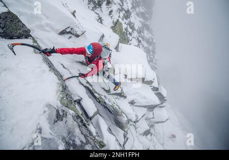 Eiskletterer, die einen steilen Abschnitt von Felsen und Eis besteigen Stockfoto