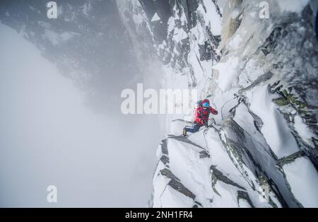 Eiskletterer, die einen steilen Abschnitt von Felsen und Eis besteigen Stockfoto