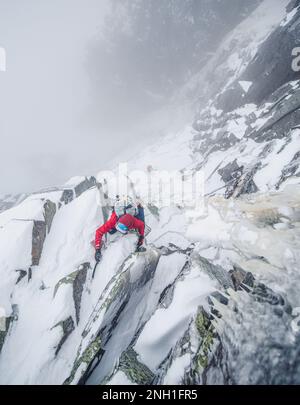Eiskletterer, die einen steilen Abschnitt von Felsen und Eis besteigen Stockfoto