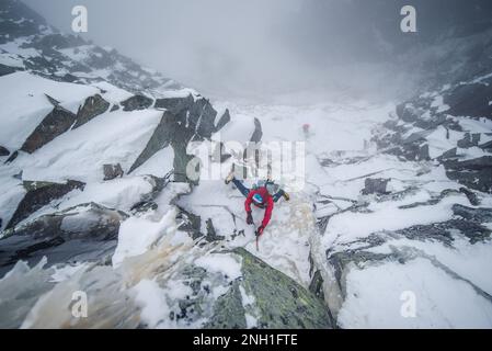 Eiskletterer, die einen steilen Abschnitt von Felsen und Eis besteigen Stockfoto