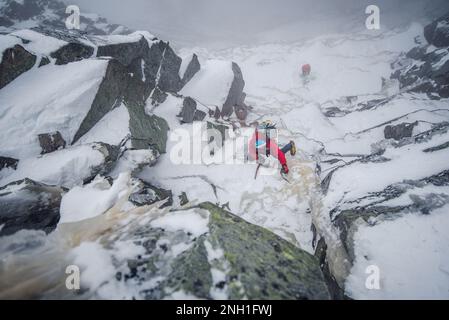 Ice climber mixed climbing a steep section of rock and ice Stock Photo