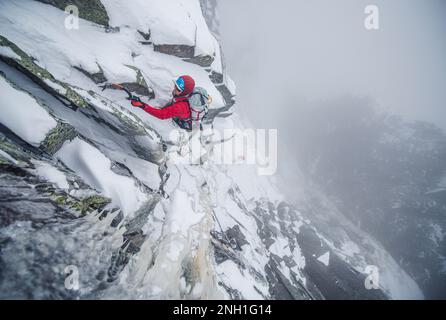 Eiskletterer, die einen steilen Abschnitt von Felsen und Eis besteigen Stockfoto