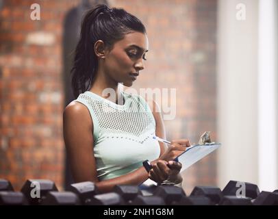 Alle Fitness-Fans Herzlich Willkommen. Eine junge Frau, die Inventur macht, während sie in einem Fitnessstudio arbeitet. Stockfoto