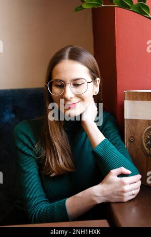 Porträt einer jungen Frau auf grünem Golf in einem Café Stockfoto