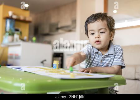 Der Junge malt mit Temperafarben in ihrem Wohnzimmer Stockfoto