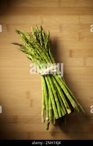 Ein Haufen wilder Spargel, gebunden mit einer Schnur, auf einem Bambustisch Stockfoto