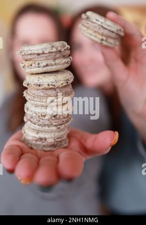 Person, die einen Stapel Makronen senkrecht hält Stockfoto