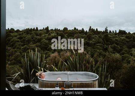 Frau in einer Badewanne im Freien, in der Nähe des Lake Taupo, Neuseeland Stockfoto