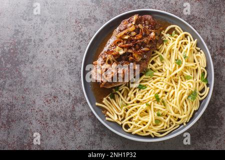 Zwiebelrostbraten deutscher Rinderbraten in Zwiebelsauce und Spaetzle Pasta auf dem Teller auf dem Tisch. Horizontale Draufsicht von oben Stockfoto