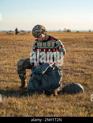 EIN US-AMERIKANISCHER Ein Fallschirmjäger der 173. Luftwaffenbrigade holt einen T-11-Fallschirm zurück, nachdem er zusammen mit den Fallschirmjägern der italienischen Armee mit den Brigata Paracadutisti „Folgore“ in Frida Drop Zone in Pordenone (Italien) eine Luftwaffenoperation durchgeführt hatte, während er am 7. Dezember 2022 einen „hässlichen Urlaubspullover“ trug. Die 173. Brigade ist die USA Die Krisenreaktionstruppe der Armee in Europa, die rasch verlegbare Truppen in die Zuständigkeitsbereiche der Vereinigten Staaten in Europa, Afrika und Zentralkommando entsendet. Forward wurde in Italien und Deutschland eingesetzt, die Brigade trainiert routinemäßig an der Seite von NATO Alli Stockfoto