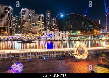 Sydney, Australien - 16. April 2022: Straßenaufführung im Darling Harbour, während das beleuchtete Sydney City Business District im Hintergrund unter zu sehen ist Stockfoto