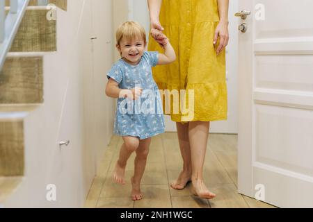 Die kleine emotionale Tochter hat zu Hause Spaß dabei, die Hand ihrer Mutter zu halten. Stockfoto