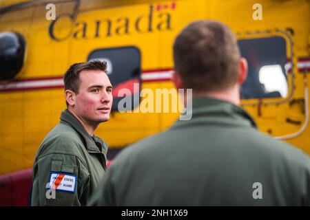 L.t. Kyle Jackson, Pilot an der Luftwaffe der Küstenwache Astoria, spricht mit L.T. Commander. Wesley Jones in der Nähe Eines Royal Canadian Air Force CH-149 Cormorant Hubschraubers an der Air Station Astoria in Warrenton, Oregon, 7. Dezember 2022. Die Flugbesatzung des Hubschraubers nahm an einer Rundfahrt durch die Flugstation Teil und nahm an einer gemeinsamen Such- und Rettungsschulung Teil. Stockfoto