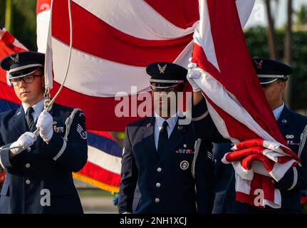 Die Flieger der Ehrengarde des 15. Flügels heben während der 81. Gedenkzeremonie des Angriffs auf Hickam Field auf der Joint Base Pearl Harbor-Hickam, Hawaii, am 7. Dezember 2022 die Farben auf die Hälfte des Personals. Der 15. Flügel ehrt weiterhin diejenigen, die die historischen Anschläge überlebt haben, diejenigen, die das ultimative Opfer gebracht haben, und ihre Familien und erinnert die, die derzeit dienen, an das Vermächtnis derer, die zuvor gekommen sind. Stockfoto