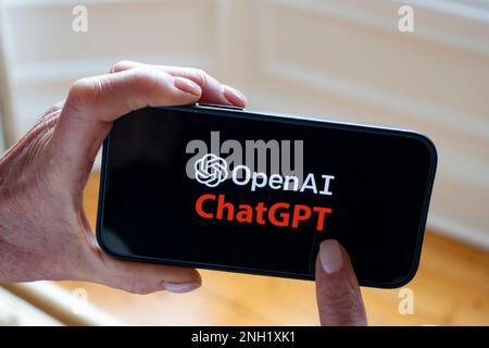 Person hat ein Mobiltelefon, auf dem das Microsoft ChatGPT OpenAI Chatbot-Logo angezeigt wird Stockfoto