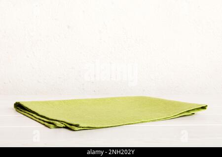 Draufsicht mit grüner Serviette auf Tischhintergrund isoliert. Gefaltetes Tuch für Modell mit Kopierbereich, flach liegend. Minimalistischer Style. Stockfoto