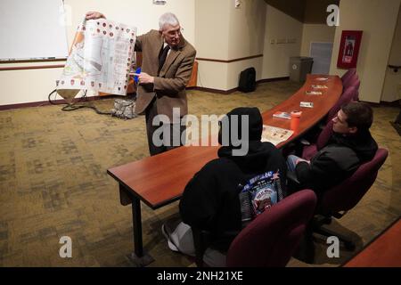 Ward Zischke, Historiker der 88. Readiness Division, weist bei einer Präsentation am 7. Dezember 2022 in Fort McCoy, Wisconsin, auf die Standorte der Schlachtschiffe hin, als die Japaner Pearl Harbor Angriff. Von links nach rechts, SPC. Robert Anderson und Sergeant Jonathan Schroeder. (Militärfoto von Cheryl Phillips) Stockfoto