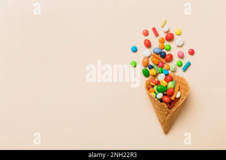 Waffelkonus voller traditioneller Süßigkeiten, die auf farbigen Hintergrund fallen, mit Platz für Kopien. Frohes Weihnachtsangebot. Stockfoto