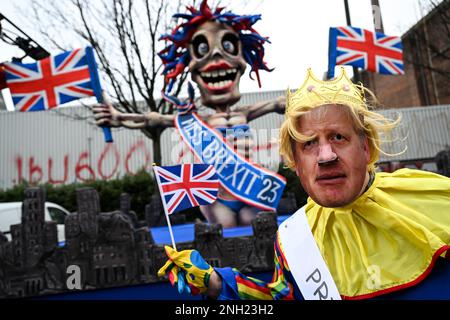 Düsseldorf, Deutschland. 20. Februar 2023. Eine Karnevalsarbeiterin aus Großbritannien, gekleidet als Ex-Premierminister Boris Johnson, steht vor dem "Miss Brexit '23" Floß. Düsseldorf veranstaltet seit drei Jahren seine erste Rose Monday Parade; 2021 und 2022 wurden die Paraden aufgrund von Corona abgesagt. Kredit: Federico Gambarini/dpa/Alamy Live News Stockfoto