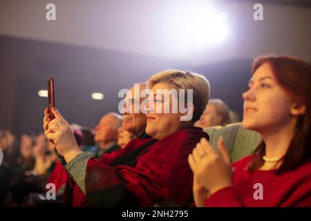 Belarus, Stadt Gomil, 01. April 2022. Zuschauer im Auditorium, die das Konzert ansehen, mit einem Smartphone Filmen... Stockfoto