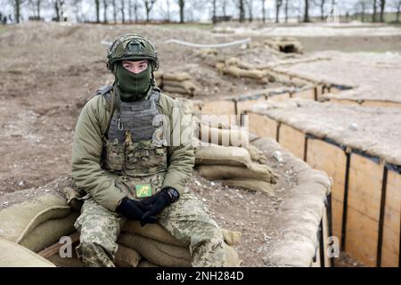 Ein ukrainischer Soldat sitzt auf Sandsäcken neben einem Schützennetz, das für die Ausbildung ukrainischer Truppen in Wiltshire verwendet wird, während einer fünfwöchigen Grundausbildung britischer und internationaler Partnerstreitkräfte, bevor er in die Ukraine zurückkehrt. Foto: Montag, 20. Februar 2023. Stockfoto