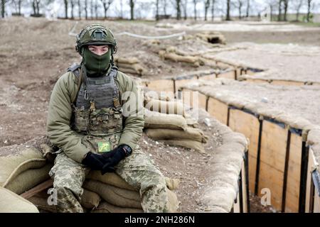 Ein ukrainischer Soldat sitzt auf Sandsäcken neben einem Schützennetz, das für die Ausbildung ukrainischer Truppen in Wiltshire verwendet wird, während einer fünfwöchigen Grundausbildung britischer und internationaler Partnerstreitkräfte, bevor er in die Ukraine zurückkehrt. Foto: Montag, 20. Februar 2023. Stockfoto