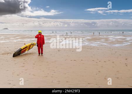 Ein RNLI-Rettungsschwimmer im Dienst an einem kühlen Fistral Beach in Newquay in Cornwall, England, Großbritannien. Stockfoto