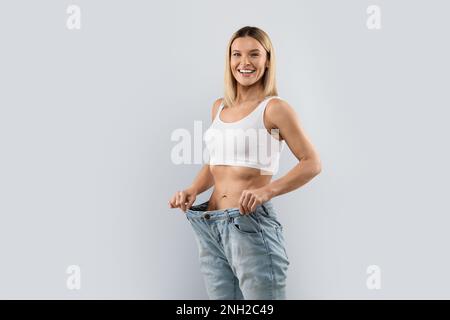 Glückliche Frau mittleren Alters, die nach Gewichtsverlust große Jeans trägt Stockfoto