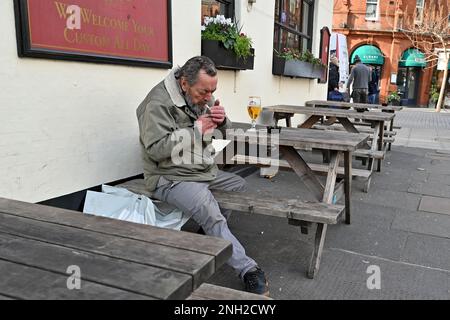 Ein Mann sitzt mit einem Pint Bier vor einem Pub in Chelsea, London. UK. Februar 2023. Stockfoto