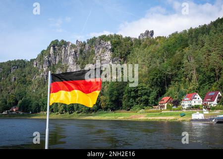 Deutsche Flagge vor dem Elbsandsteingebirge in Rathen bei der Bastei-Brücke (Basteibrücke) - Sachsen, Deutschland Stockfoto