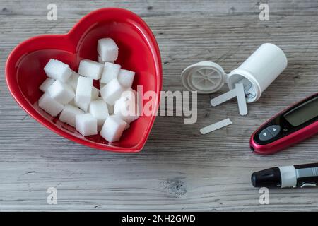 Herzförmige Schüssel und Zuckerwürfel. Diabetes-Testung Stockfoto