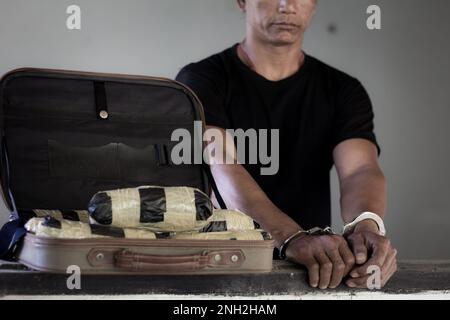 Drogenhändler wurden zusammen mit ihrem Heroin verhaftet. Die Polizei verhaftete Drogenhändler mit Handschellen. Kriminalitätsbegriff und Drogensucht. 26. Juni Stockfoto