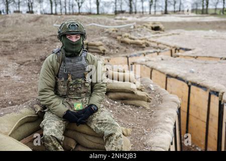 Ein ukrainischer Soldat sitzt auf Sandsäcken neben einem Schützennetz, das für die Ausbildung ukrainischer Truppen in Wiltshire verwendet wird, während einer fünfwöchigen Grundausbildung britischer und internationaler Partnerstreitkräfte, bevor er in die Ukraine zurückkehrt. Foto: Montag, 20. Februar 2023. Stockfoto