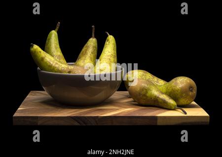 Birnen in einer Schüssel und auf einem Holzbrett, isoliert auf schwarzem Hintergrund Stockfoto