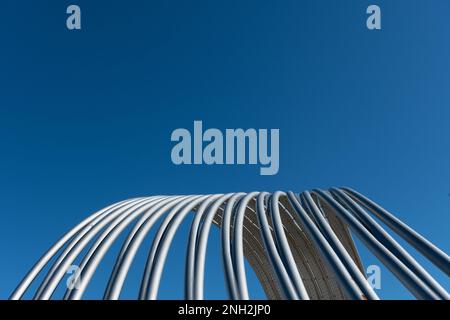 Aluminiumrohre, die sich über dem Kopf gegen den reinen und tiefblauen Himmel bogen. Stockfoto