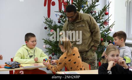 Greywolf Trooper, SPC. Tyrell Kinley, Hauptquartier und Hauptquartier, 215. Brigadestützbataillon, 3. Kampfteam der Panzerbrigade, 1. Kavallerieabteilung, interagiert mit polnischen Schülern der Grundschule. Major H. Sucharskiego, 9. Dezember 2022. Ereignisse wie diese stärken weiterhin die Bande zwischen der polnischen Gemeinschaft und der US-Armee. Stockfoto