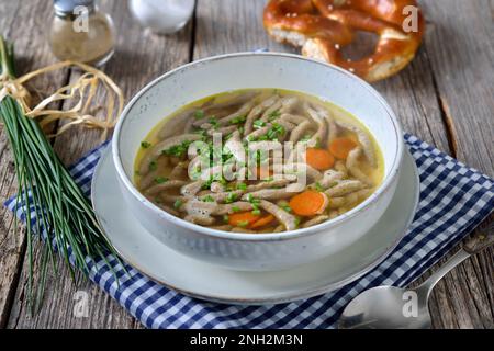 Bayrisches, schwäbisches und österreichisches Gericht - Leberspaetzle in einer Rindersuppe mit knuspriger Brezel Stockfoto