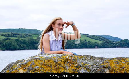 An einem wunderschönen Oktobertag in Wormit Beach, Fife, sitzt Rhianna Martin auf großen Felsen am Fluss Tay, Schottland Stockfoto