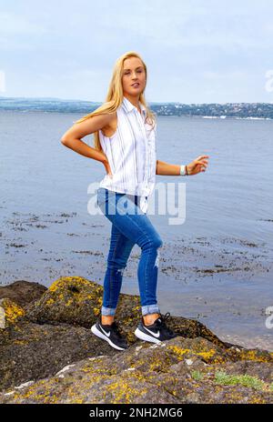 An einem wunderschönen Oktobertag in Wormit Beach, Fife, steht Rhianna Martin auf großen Felsen neben dem Fluss Tay, Schottland Stockfoto