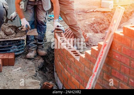 Maurer, der an einer gebogenen Wand auf der Baustelle arbeitet Stockfoto