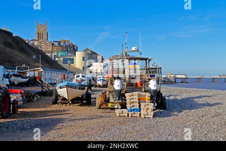 Ein Blick auf lokale Küstenfischereiboote, die über dem Hochwasserrand an der Nordnorfolkküste bei Cromer, Norfolk, England, Vereinigtes Königreich, liegen. Stockfoto