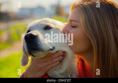 Belgrad, Serbien. 10. November 2022. Wunderschöne junge Frau, die ihren süßen Golden Retriever an einem sonnigen Tag draußen küsst. Stockfoto