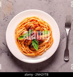 Spaghetti mit Fleischbällchen und Tomatensauce auf Steinhintergrund, Draufsicht Stockfoto