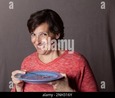 Ältere Frau mit leerem blauem Teller Stockfoto