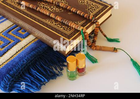 Heiliger koran und Gebetsrosenkranz auf Gebetsmatte auf weißem Hintergrund. Islamisches Konzept. ramadan-Karäem Stockfoto