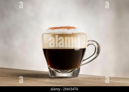 Cappuccino in Glasbecher auf Holztisch Stockfoto